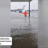 Man stands knee deep in water on runway at Majorca airport.