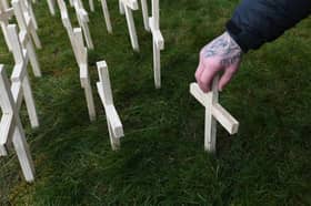 A man leaves a cross for his brother during an event to mark those who lost their lives to drugs in Scotland at Springburn Parish Church in Glasgow