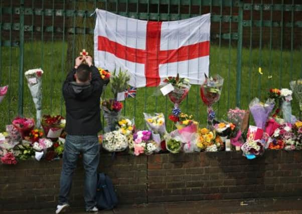 A member of the public fixes a poppy to tributes left for murdered soldier Lee Rigby. Picture: Getty