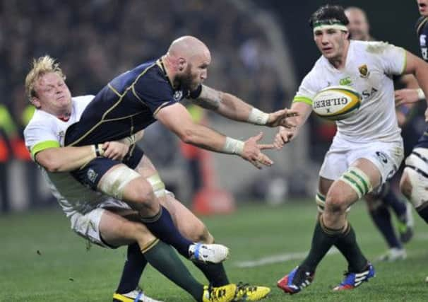 Alisdair Strokosch throws the ball away despite the tackle by Springbok hooker Adriaan Strauss. Picture: Getty