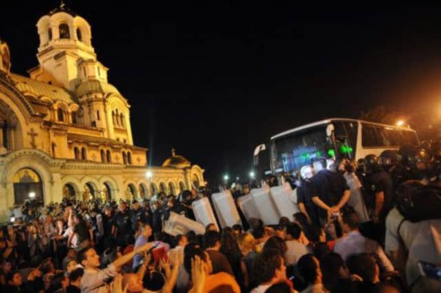 Bulgarian riot police push protesters out of the way of a bus carrying MPs out of the parliament precinct. Picture: AFP/Getty