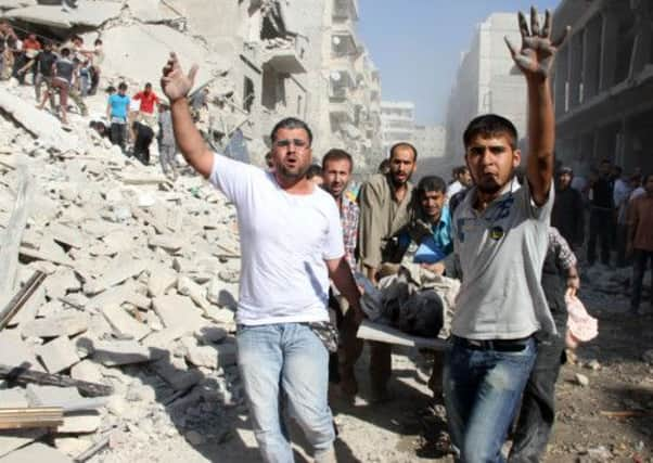 Syrian men evacuate a victim following an air strike by Assad forces in the northern city of Aleppo. Picture: Getty/AFP