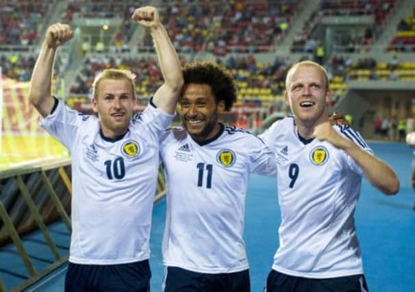 Barry Bannan and Steven Naismith help Ikechi Anya celebrate his goal. Picture: SNS