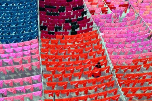 A worker hangs clothes to dry on the roof of a Dhaka garment factory. Picture: Rafiqur Rahman/Reuters