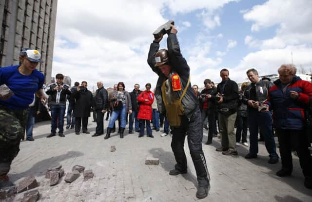 A proRussia protester breaks a stone at a barricade outside a regional government building in Donetsk. Picture: Reuters