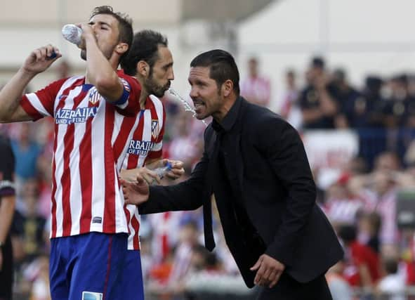 Atletico Madrids Argentinian coach Diego Simeone talks to his midfielder Juanfran and captain Gabi. Picture: AFP/Getty