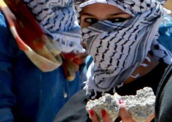 Palestinian women gather stones to throw at an Israeli guard tower in Bethlehem yesterday. Picture: AFP/Getty