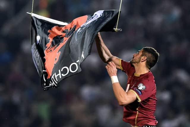 Serbias Stefan Mitrovic grabs a flag with Albanian national symbols flown by a remotely-operated drone. Picture: Getty