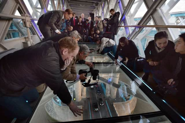 Members of the media capture the view from the newly installed glass floor 138 feet above the River Thames at Tower Bridge. Picture: PA