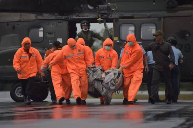 Indonesian search and rescue team members with items for investigation found during the hunt for AirAsia Flight 8501. Picture: AFP/Getty