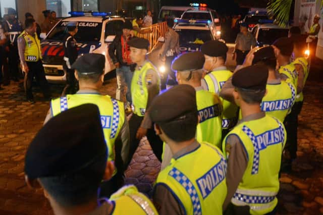 Police guard the ambulances taking the bodies for burial. Picture: Getty