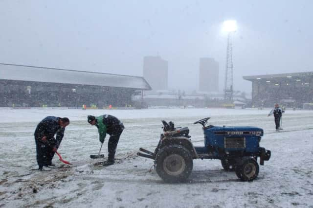 Snow is swept off the pitch at Dens Park before a scheduled fixture between Dundee and Hibernian is abandoned in 2003. Picture: Phil Wilkinson