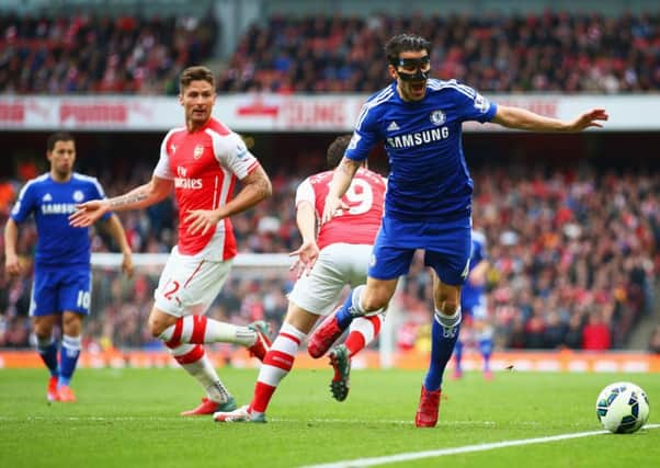 Cesc Fabregas, wearing a special protective face mask, is challenged by Santi Cazorla. Picture: Getty