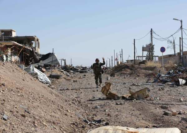 A Kurdish peshmerga fighter flashes a victory sign as he walks through the town of Sinjar yesterday. Picture: AP