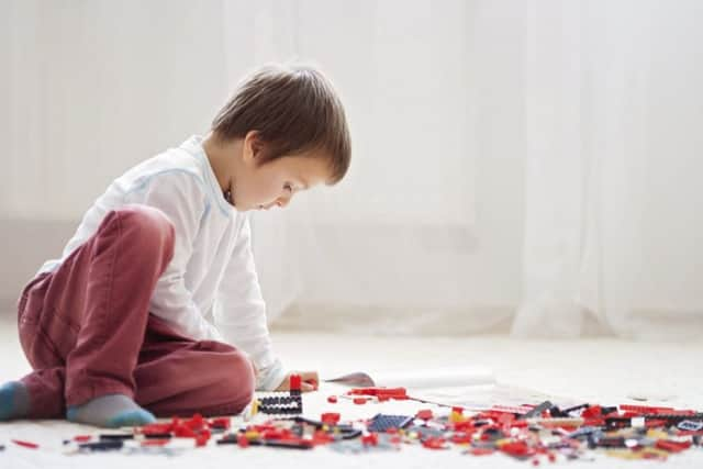 Little child playing with lots of colorful plastic blocks indoors.