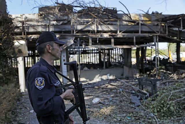 A Turkish policeman stands guard in front of a damaged building inside a special forces base which was attacked by warplanes during the failed military coup. Picture: AP Photo/Hussein Malla