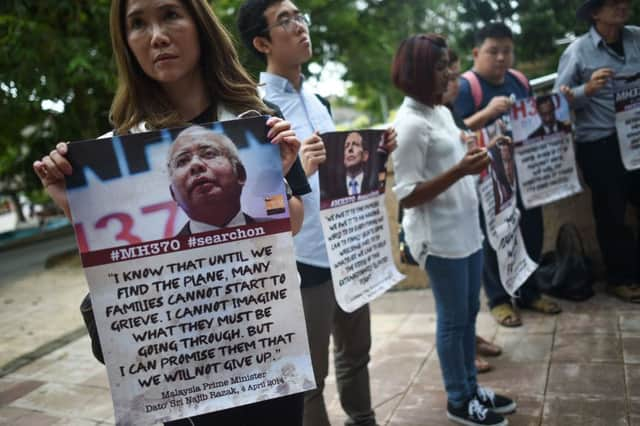 Relatives of passengers on Malaysia Airlines Flight MH370 hold placards urging the search to go on. Picture: AFP/Getty