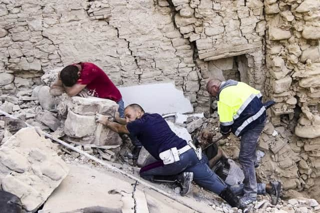 A man cries as another injured is helped in Amatrice, central Italy. Picture: AP Massimo Percossi/ANSA via AP