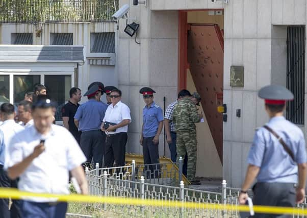 Kyrgyz police officers examine broken gates at the entrance of the Chinese Embassy in Bishkek, Kyrgyzstan. Picture: AP