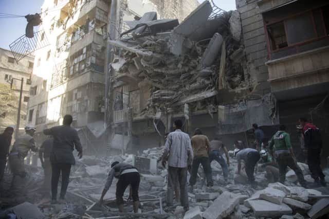 Syrian civilians and rescuers gather at site of government forces air strikes in the rebel held neighbourhood of Al-Shaar in Aleppo on September 27, 2016.  PIC: KARAM AL-MASRI/AFP/Getty Images