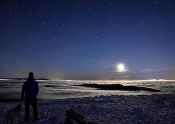 Chris Miles with his dog looking down at low cloud inversion over Tomtain from the Kilsyth Hills. Picture: SWNS