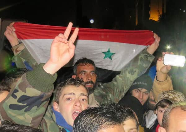 Syrians celebrate with national flags in an Aleppo's regime-held district near the al-Shuhaba roundabout. Picture: AFP PHOTO / STRINGERSTRINGER/AFP/Getty Images