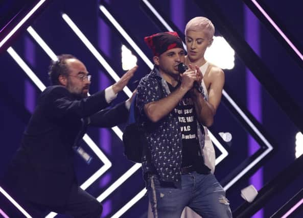 A man takes the microphone of SuRie from Great Britain, right, as a security staff approaches in Lisbon, Portugal. Picture: AP