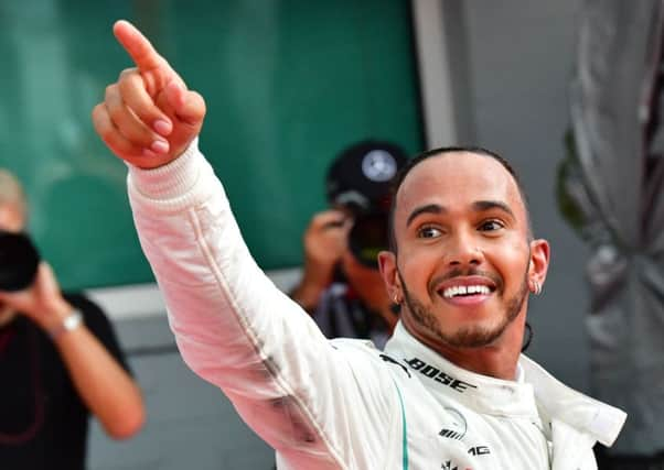 Sebastian Vettels Ferrari is lifted out of the gravel, while Lewis Hamilton,left, celebrates his famous victory. Picture: AFP/Getty.