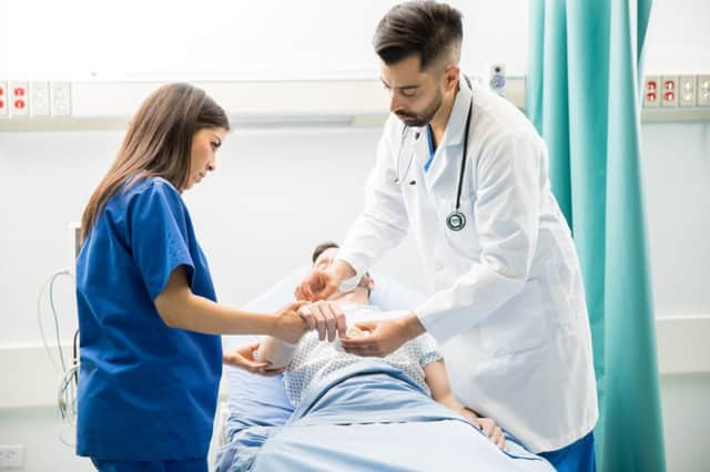 Two young doctors working on a patient in the emergency room at a UK hospital