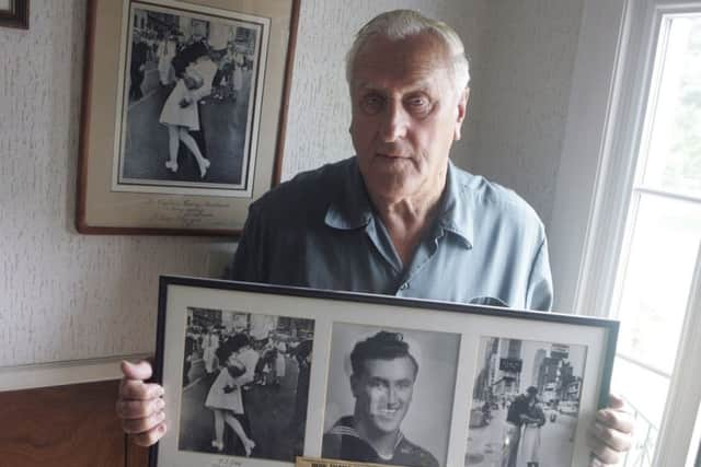 George Mendonsa poses for a photo in Middletown, R.I., holding a copy of the famous Alfred Eisenstadt photo of Mendonsa kissing a woman in a nurse's uniform in Times Square on Aug. 14, 1945. (Connie Grosch/Providence Journal via AP)