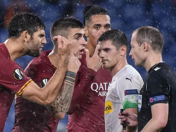 Federico Fazio (left) and Gianluca Mancini of Roma argue with Scottish referee Willie Collum.